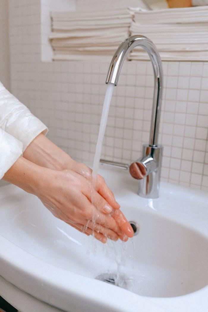 why-choose-us Close-up of a woman washing hands under a running faucet, promoting hygiene.