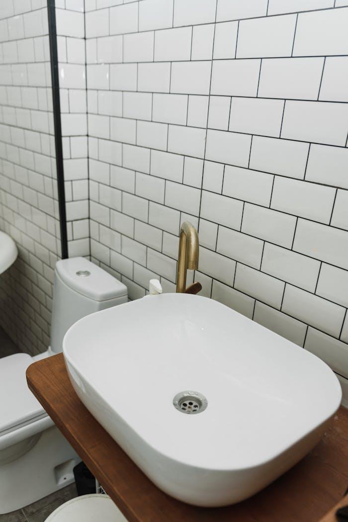 journey Stylish bathroom featuring a white ceramic sink with gold faucet and classic subway tiles.